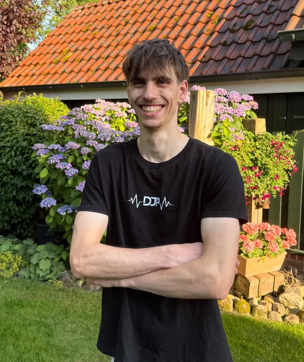 Jan-Philipp Rehring lächelnd im Garten, im schwarzen T-Shirt mit DJP-Logo